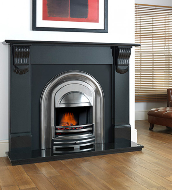 The Cast Tec Athena granite fireplace surround in black with a silver inset fire. The room has a wooden floor and white walls. There is a red and black framed abstract painting above the fireplace and a brown leather chair off to the side. 