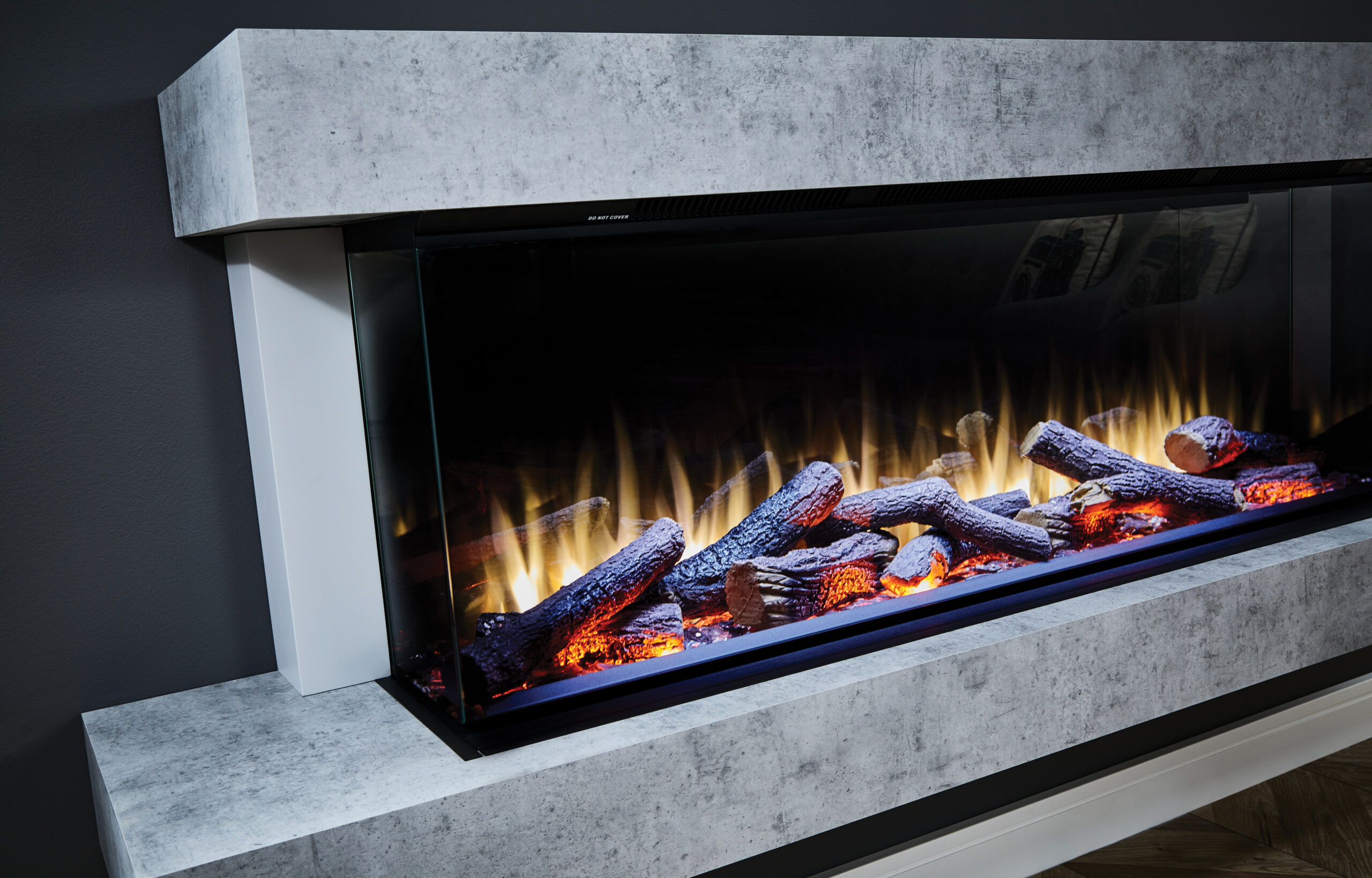A close-up image of the flame effect on the Katell Cento Italia fireplace in concrete grey. The flames are over a bed of realistic looking logs with red, yellow and purple colours. 