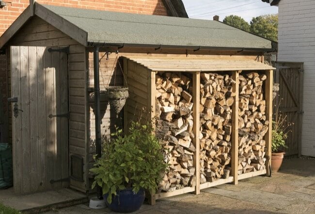 Log store in garden against shed
