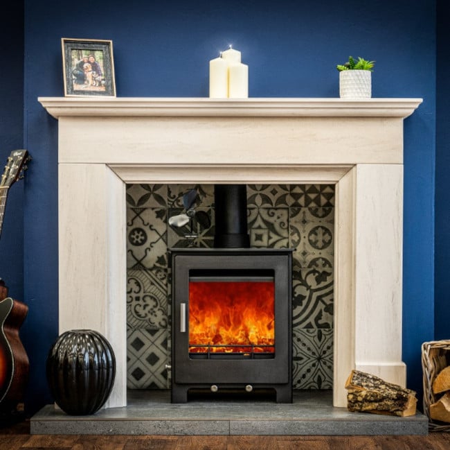 Woodford lowry 5X wood burning stove in a tiled fireplace with a cream fire surround, against a navy blue wall