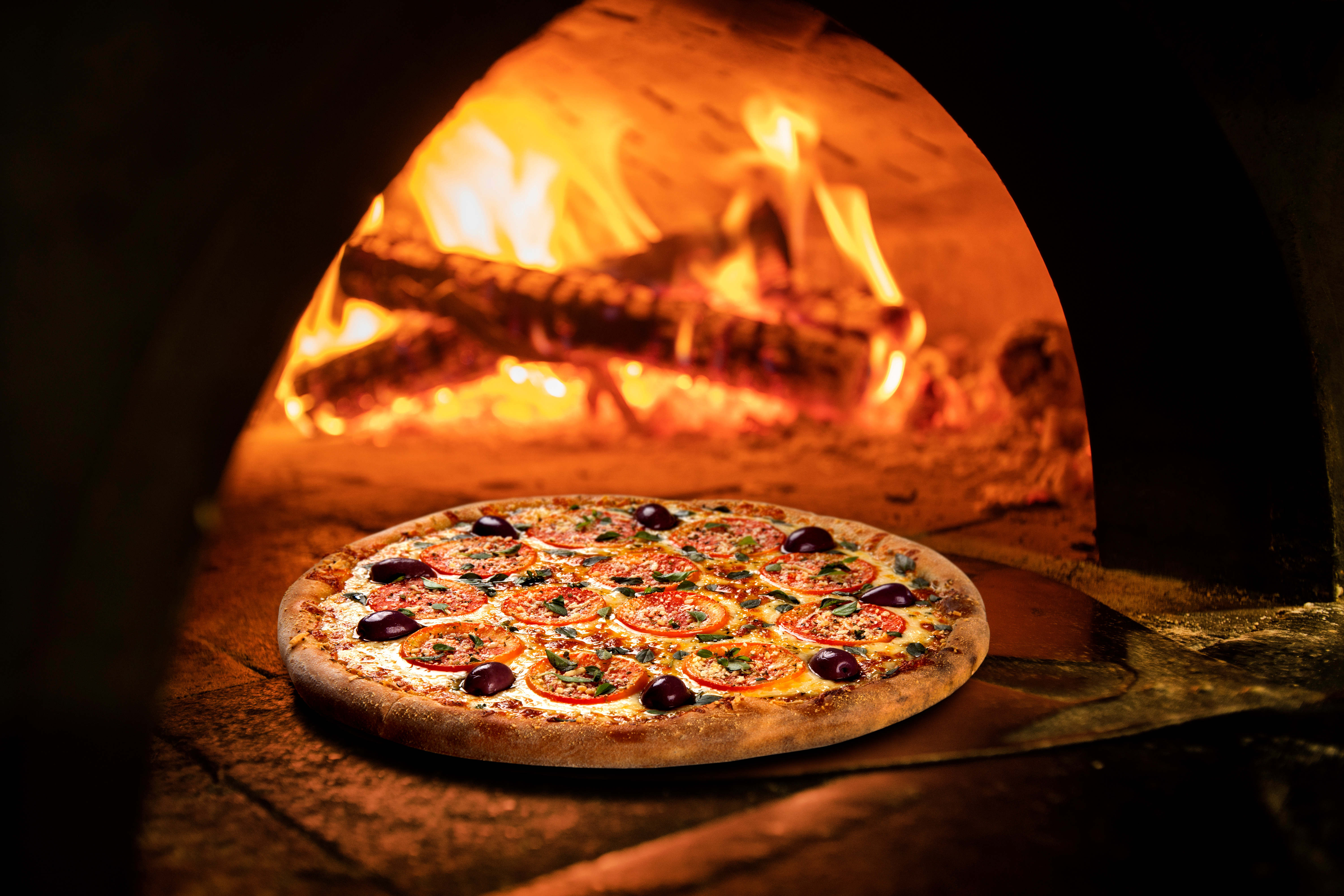 Image of a brick pizza oven with fire.